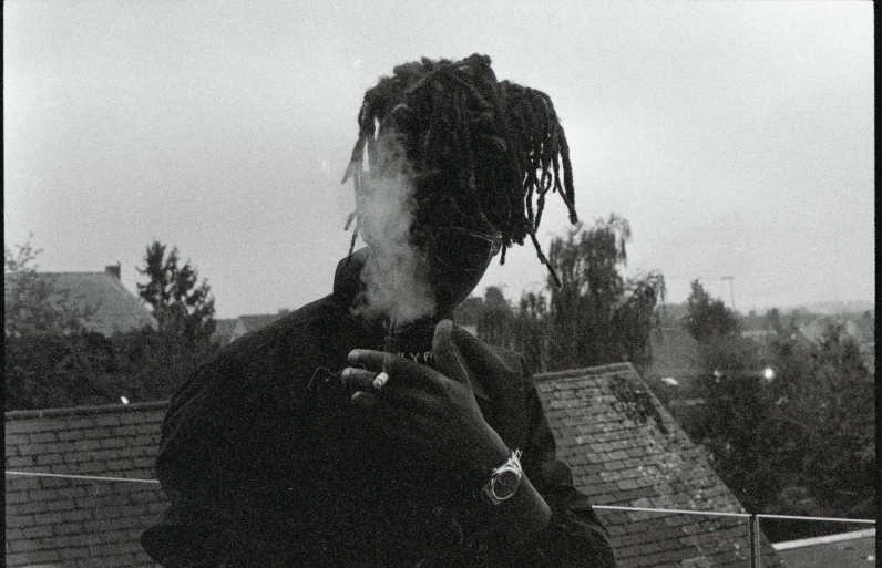 a man with dreadlocks talks on his phone while smoking