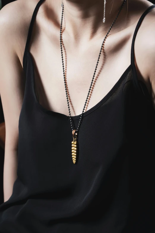 a woman wearing a black top has a brown necklace with gold accents