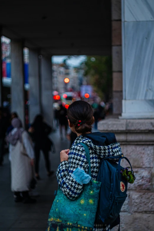 a girl in a blue and white jacket stands next to a sidewalk