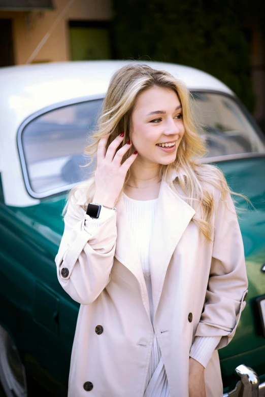 a woman in a beige coat is talking on a cell phone