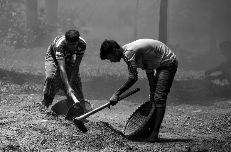 a couple of men standing next to each other holding rakes