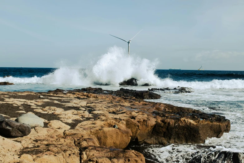 there is a small wave that is crashing over some rocks