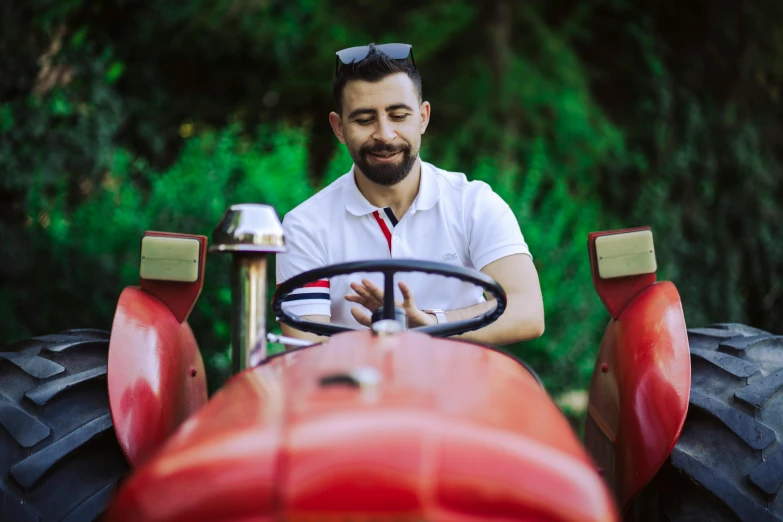 a man wearing red gloves, sits in an old fashioned tractor