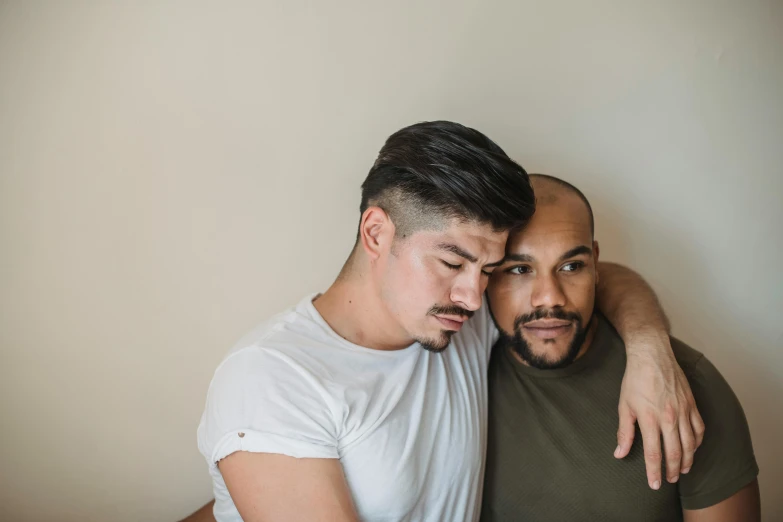 two men hugging each other in front of a wall