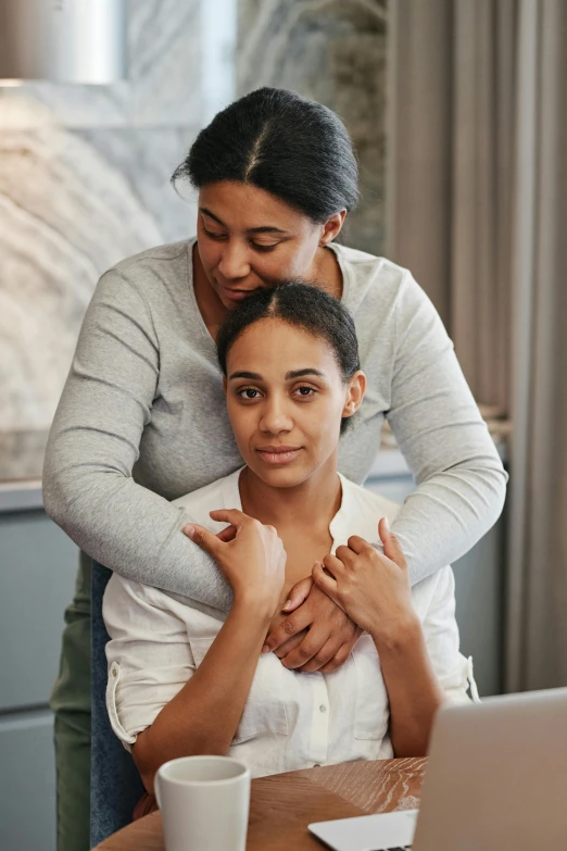 a woman smiling while hugging her friend from behind