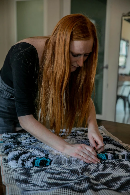 a woman is working on a homemade piece of fabric