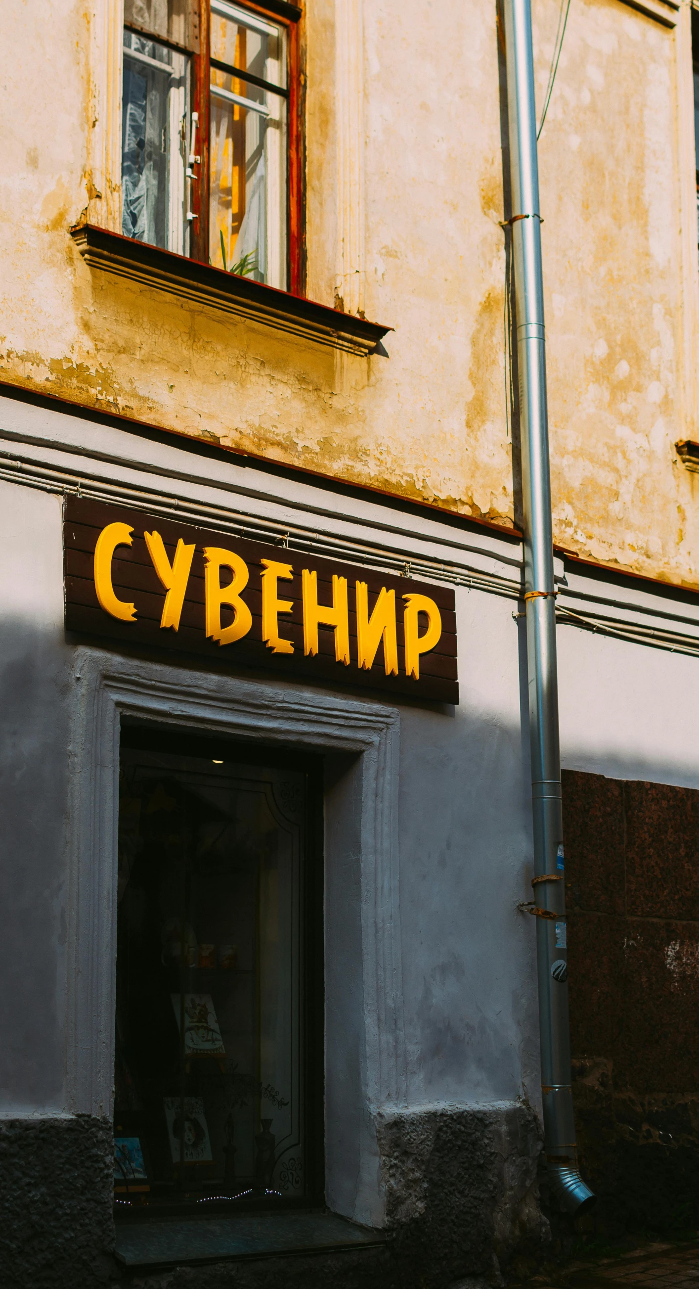 a small shopfront with bright yellow letters is next to an old building