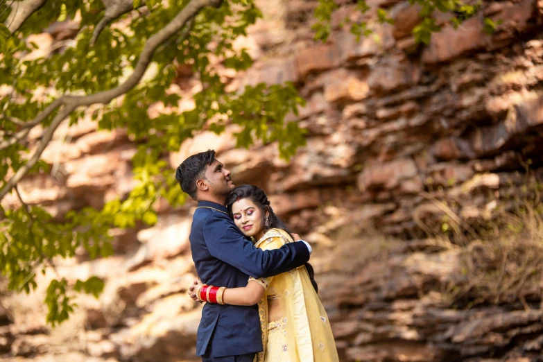 a couple is cuddling near the rock formation during their indian wedding session