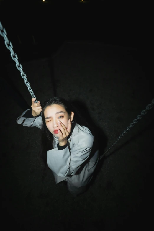  in a grey shirt holding a rope attached to a pole at night