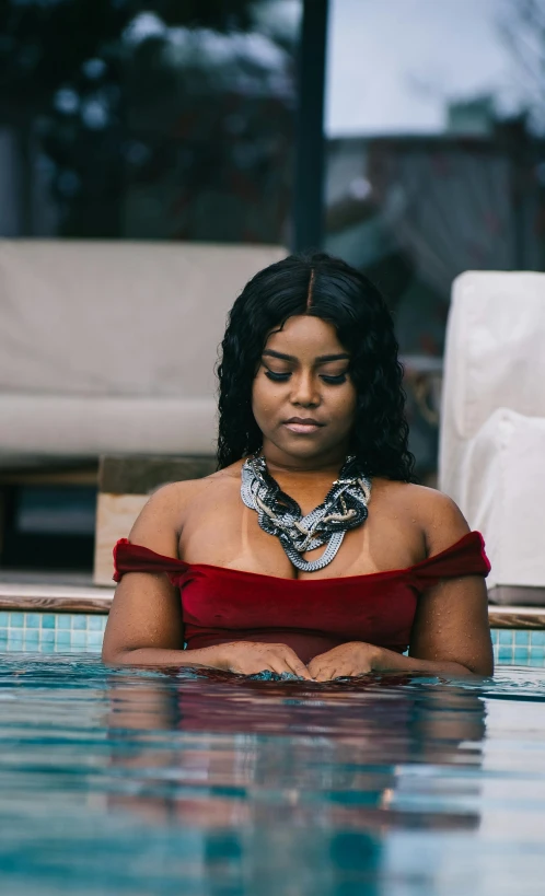 a woman sitting in the water with her head resting on her hands