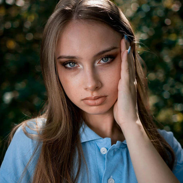 a girl with long hair holding her face to her left side