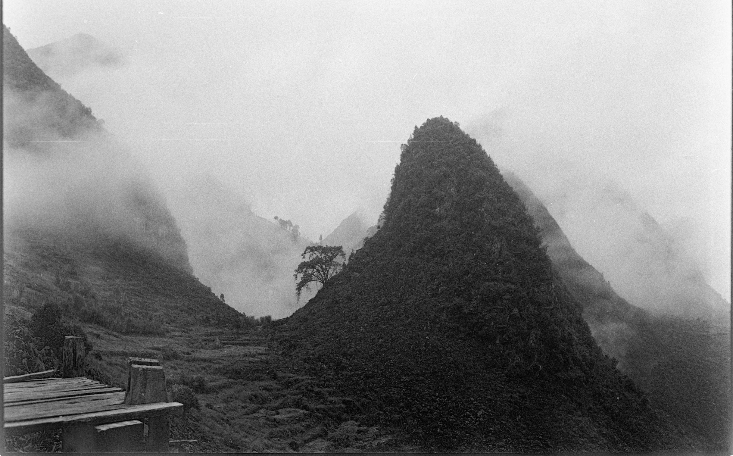 fog rises from mountains as a building sits near it