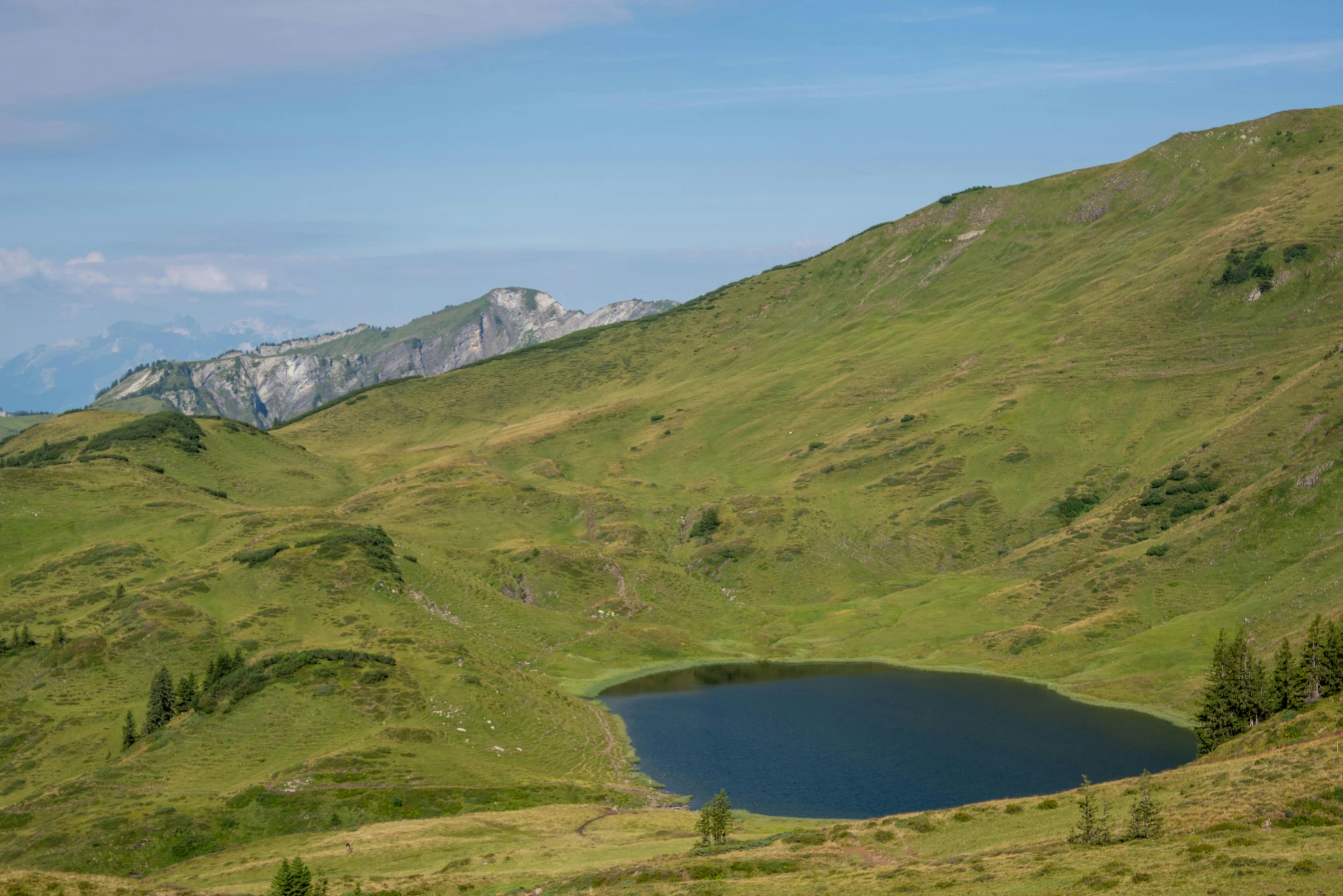 a grassy landscape with hills, a lake and mountains