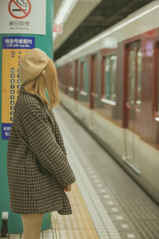 woman wearing a plaid coat and hat waiting to go on the train