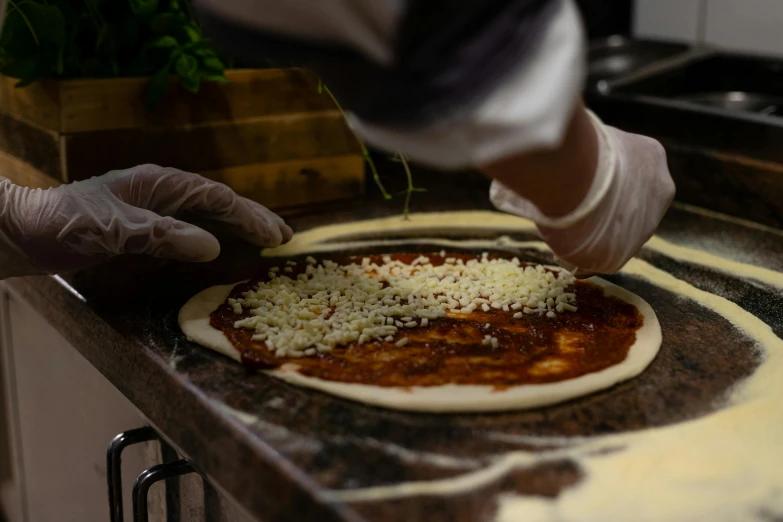 someone preparing pizzas with lots of cheese on top