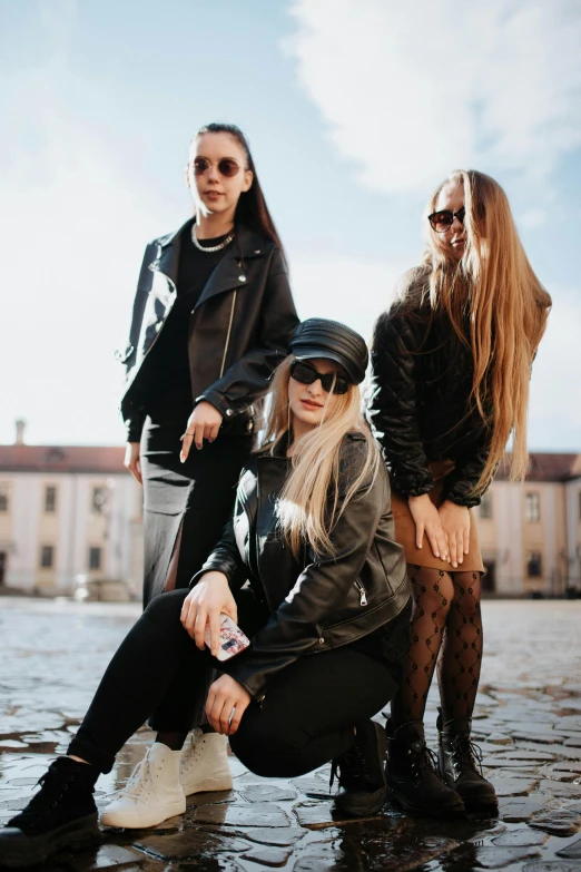 three women are sitting on the pavement in the rain