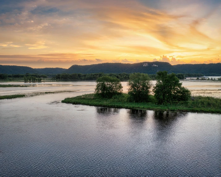 an island sits near the water as the sun goes down