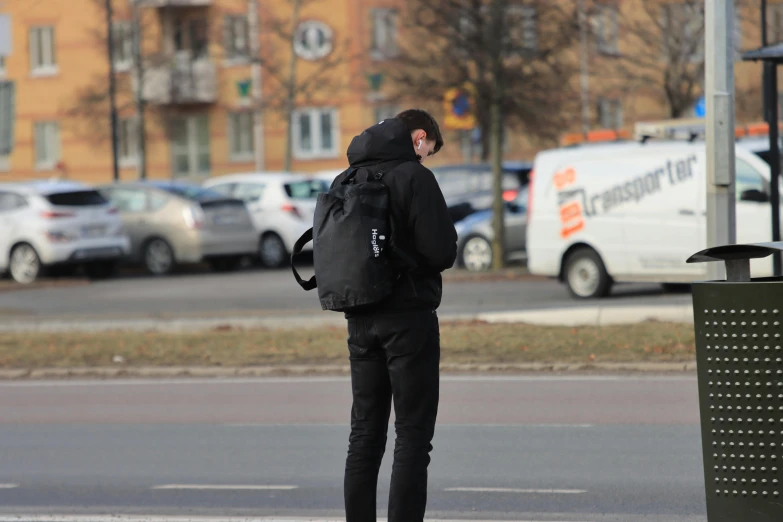a person with a backpack is standing at a crosswalk