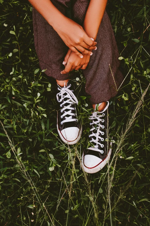 the woman is sitting in the grass wearing tennis shoes