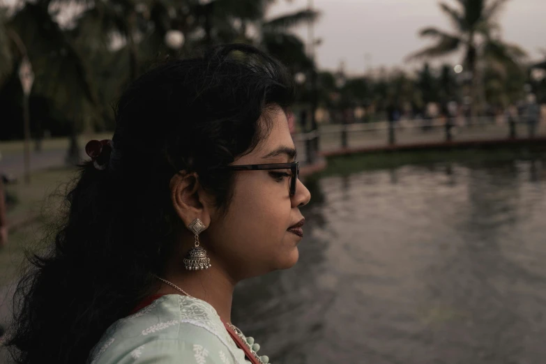 an indian woman staring into the distance near water