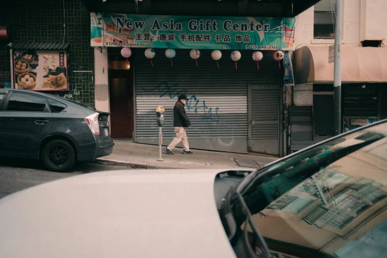 a woman walking down a city street past a parked car