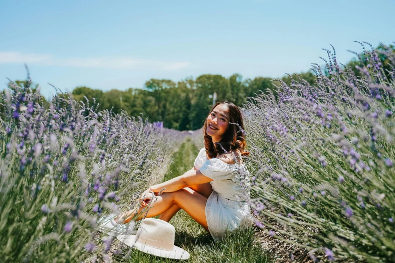 a woman sitting on a field of lavender flowers