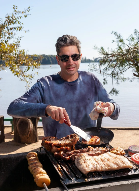 a man cooking steaks on a grill outside