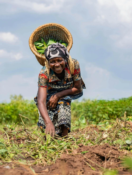 a woman in the fields carrying a straw hat