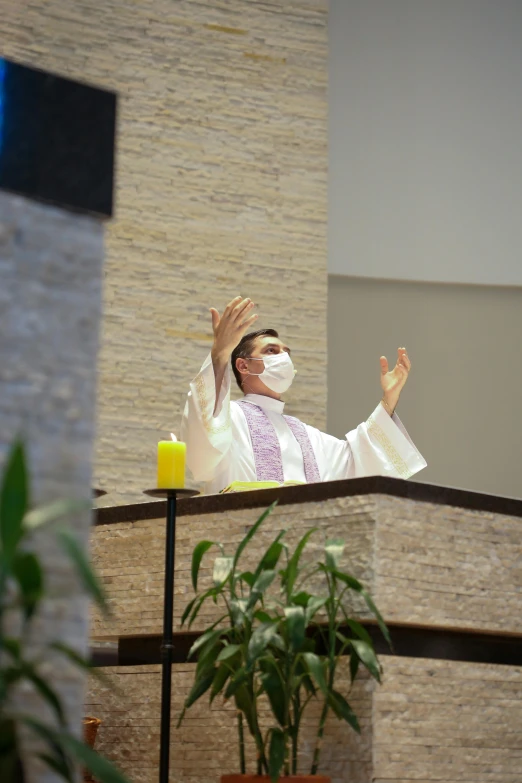 a priest in white with his hands together