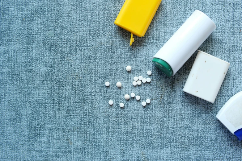 two medicine bottles and some white pills sitting on a blue blanket