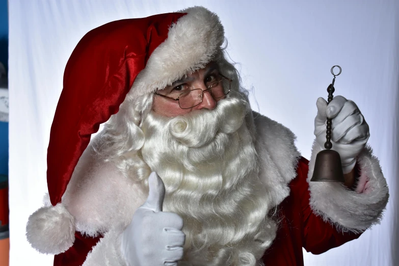 a man dressed in a santa suit and holding a bell