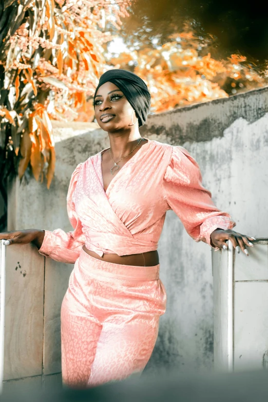 a woman in an pink dress standing by a tree