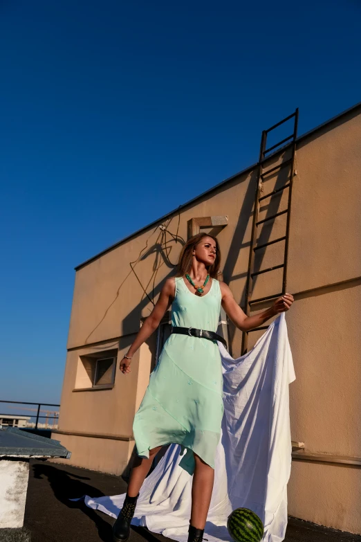 a woman wearing a mint green dress holding up a white dress