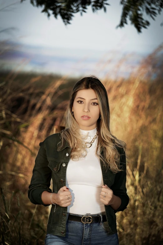 the woman is posing by some tall grass