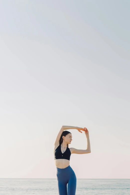 a woman standing on the beach doing yoga poses