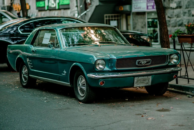 an old ford mustang sitting on the side of the road