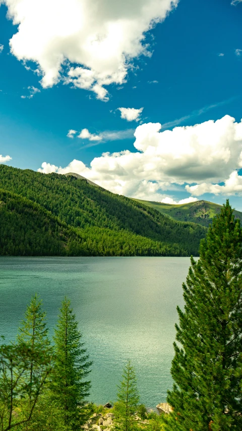 the lake is surrounded by hills and trees