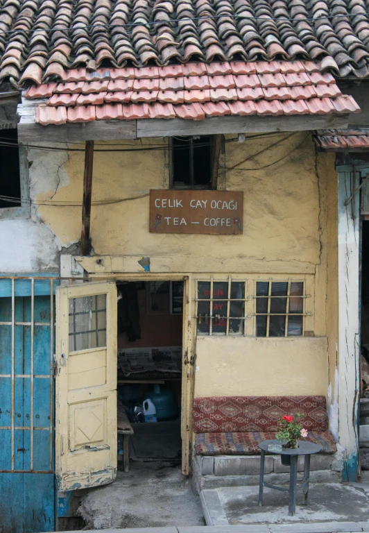 a yellow building with blue doors has a wooden table and benches near it