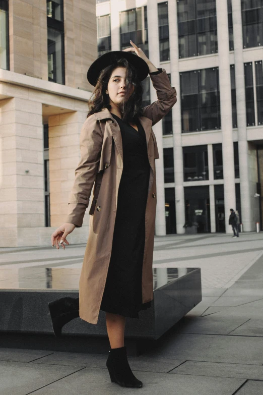 a woman is dressed in a trench coat and a hat