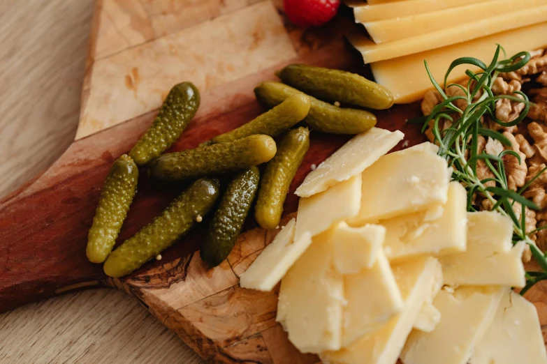 a wood  board with cheese and pickles