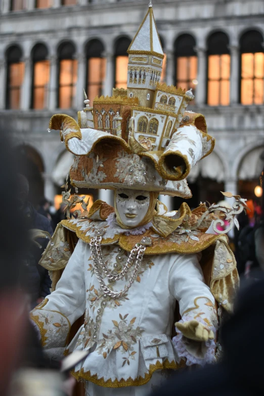 a white and gold mask with a clock tower in the background