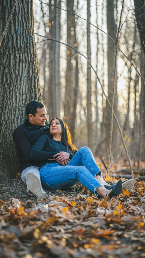 a man and woman hugging by a tree in the woods