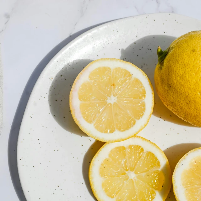 a plate with three slices of lemon and a whole lemon on it