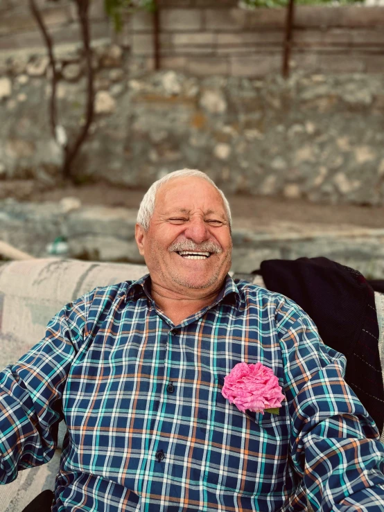 an older man with a rose in his pocket smiles at the camera