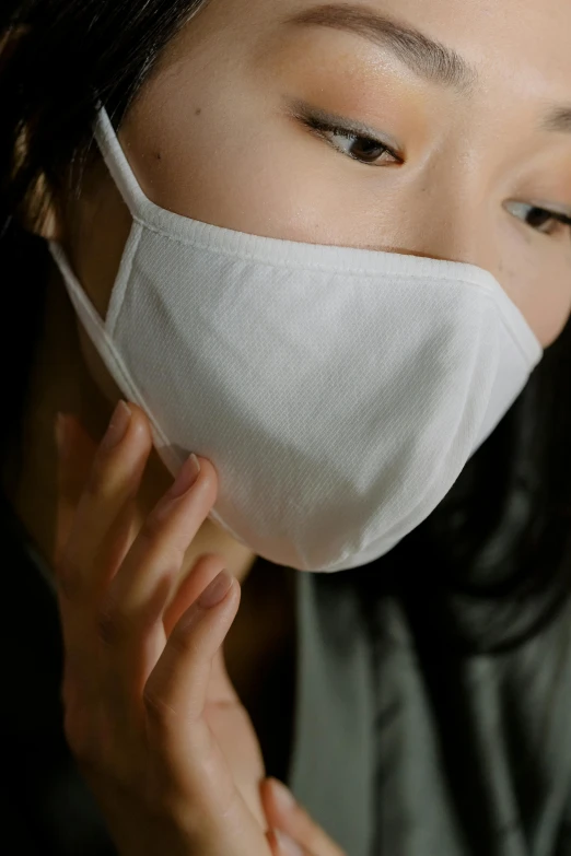 a woman in a grey top with a white mask on her face