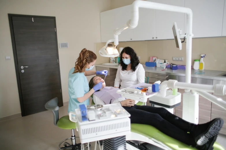 three women with dental masks are sitting and having their teeth checked