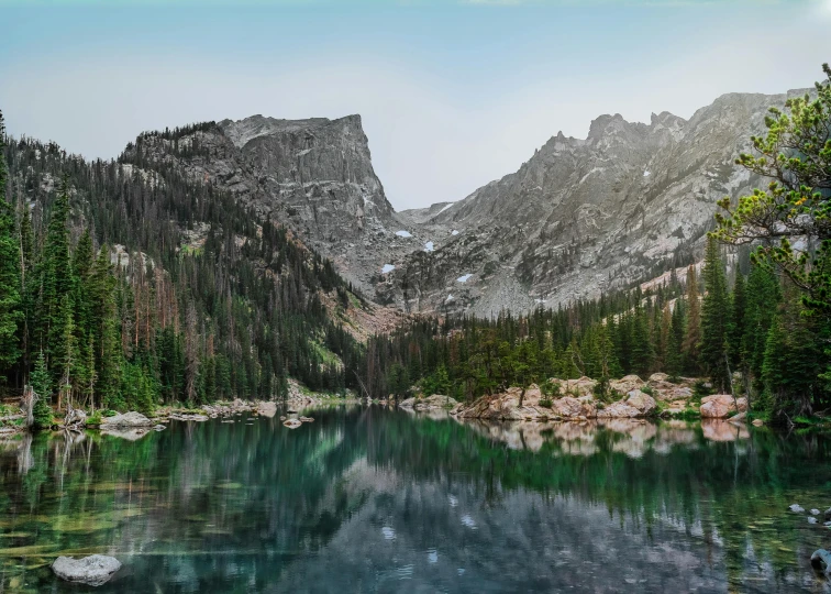 the mountain range can be seen over a still water stream