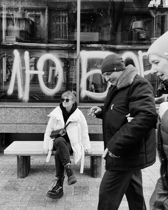 a group of people sit on benches in front of a graffiti covered building