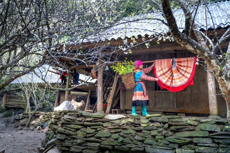 an asian woman standing outside of her house in the countryside