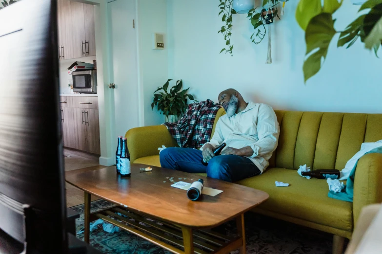 a man sitting on top of a green couch next to a table